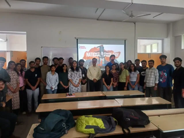 "Group photo of students and faculty at Shoolini University celebrating National Space Day 2025 with a presentation in the background."